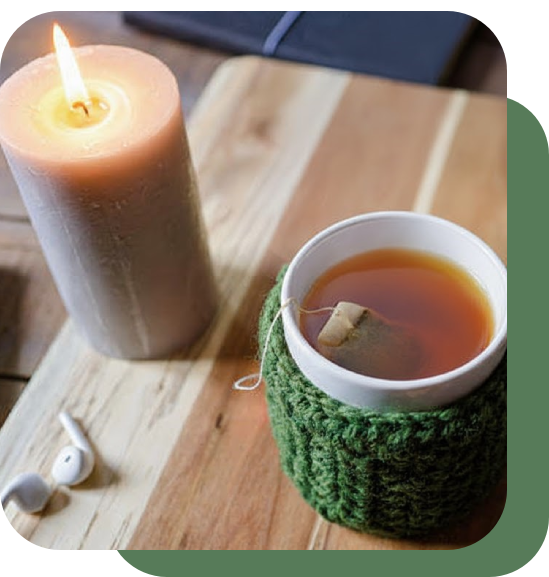 A cozy cup of tea beside a lit candle on a wooden table.