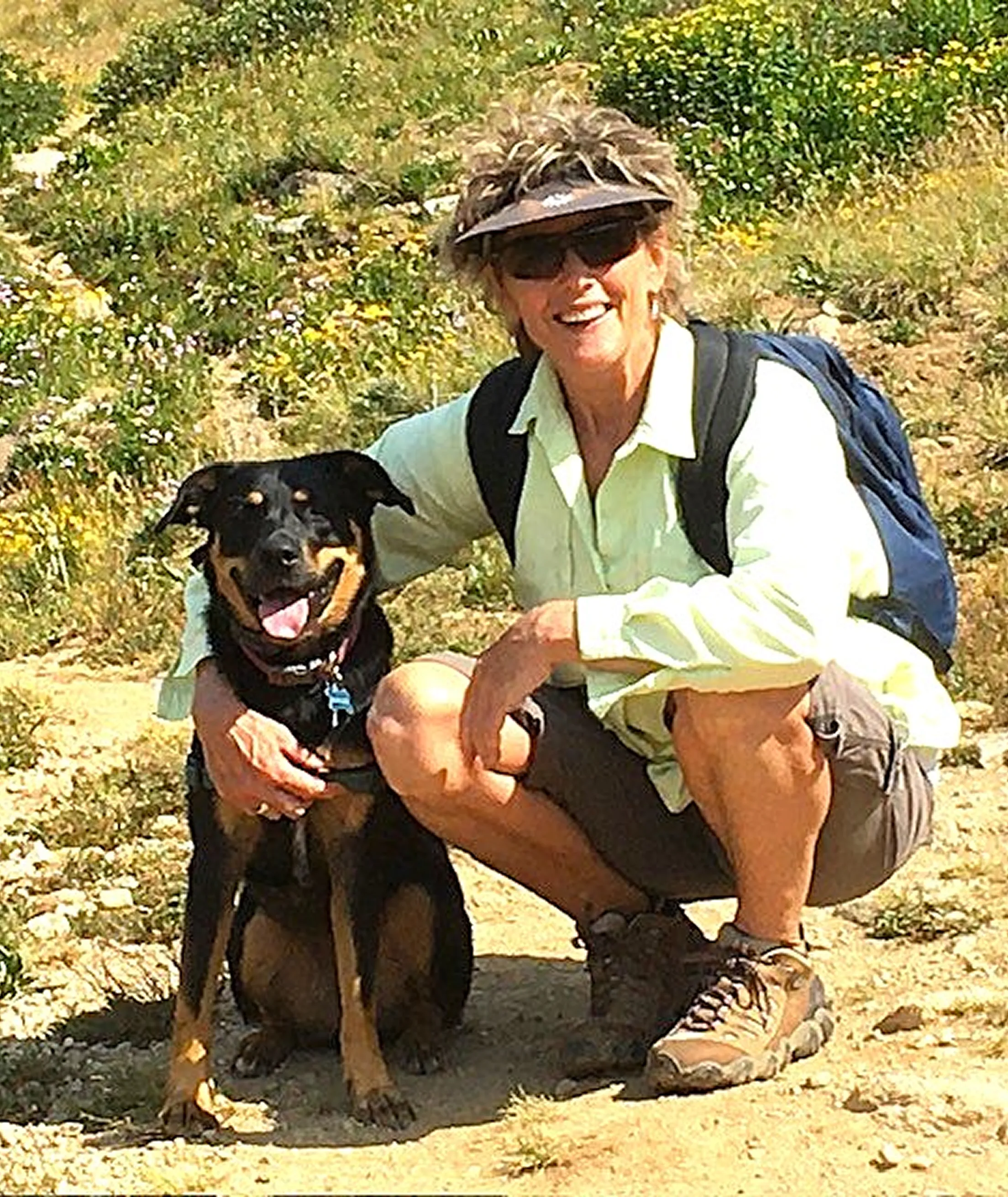 Woman hiking outdoors with her dog on a sunny day.